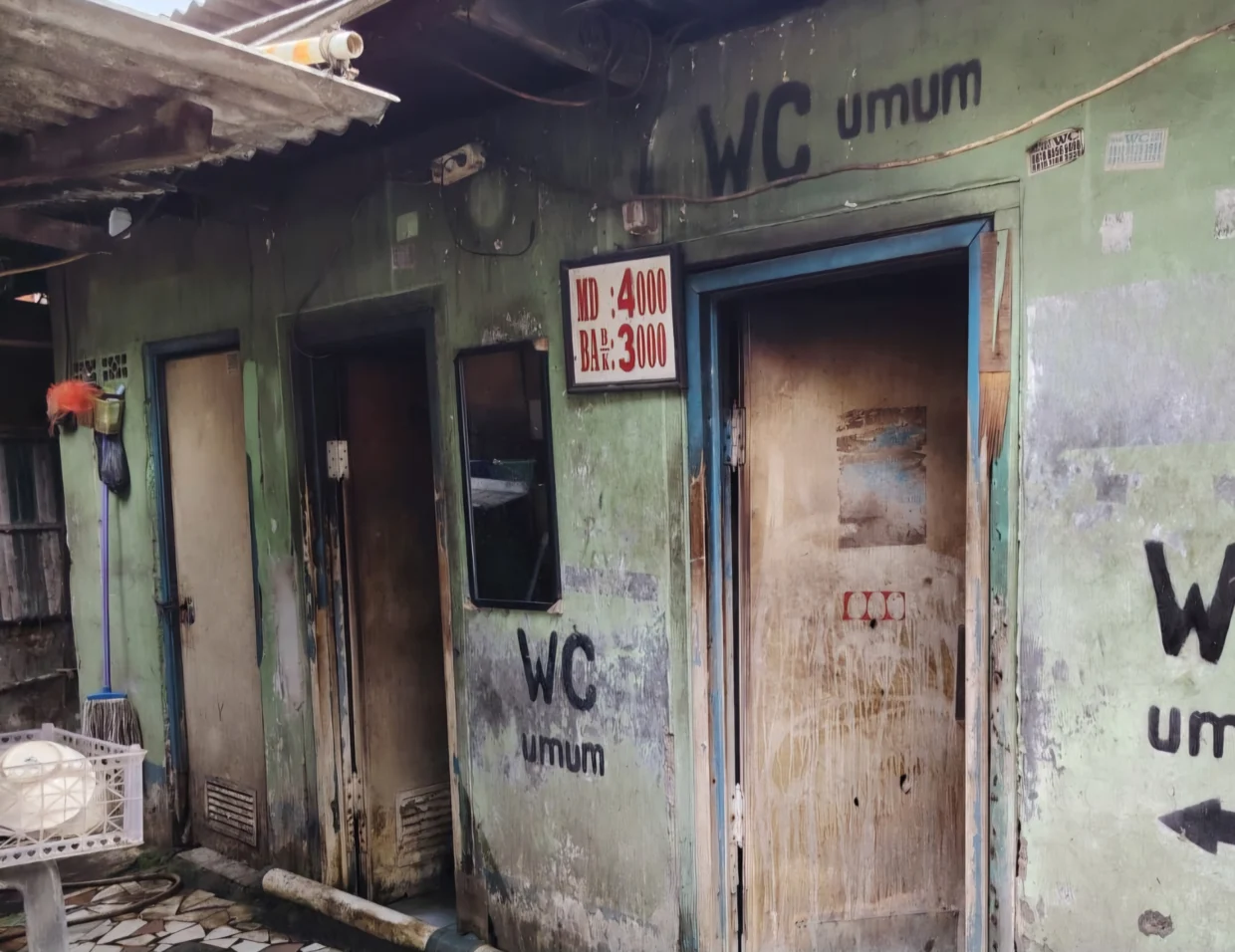 WC umum berbayar di Jalan Peta Selatan, Kalideres, Jakarta Barat, dengan tarif mandi Rp4.000 dan BAB Rp3.000, yang diduga berdiri di atas lahan aset Pemda DKI Jakarta di samping Swalayan Hari Hari dan pagar sekolah dasar.